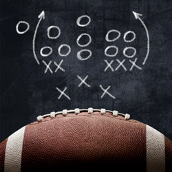 A football with a play written on a chalkboard, representing the unique considerations and obstacles faced by professional athletes and their spouses during a divorce.